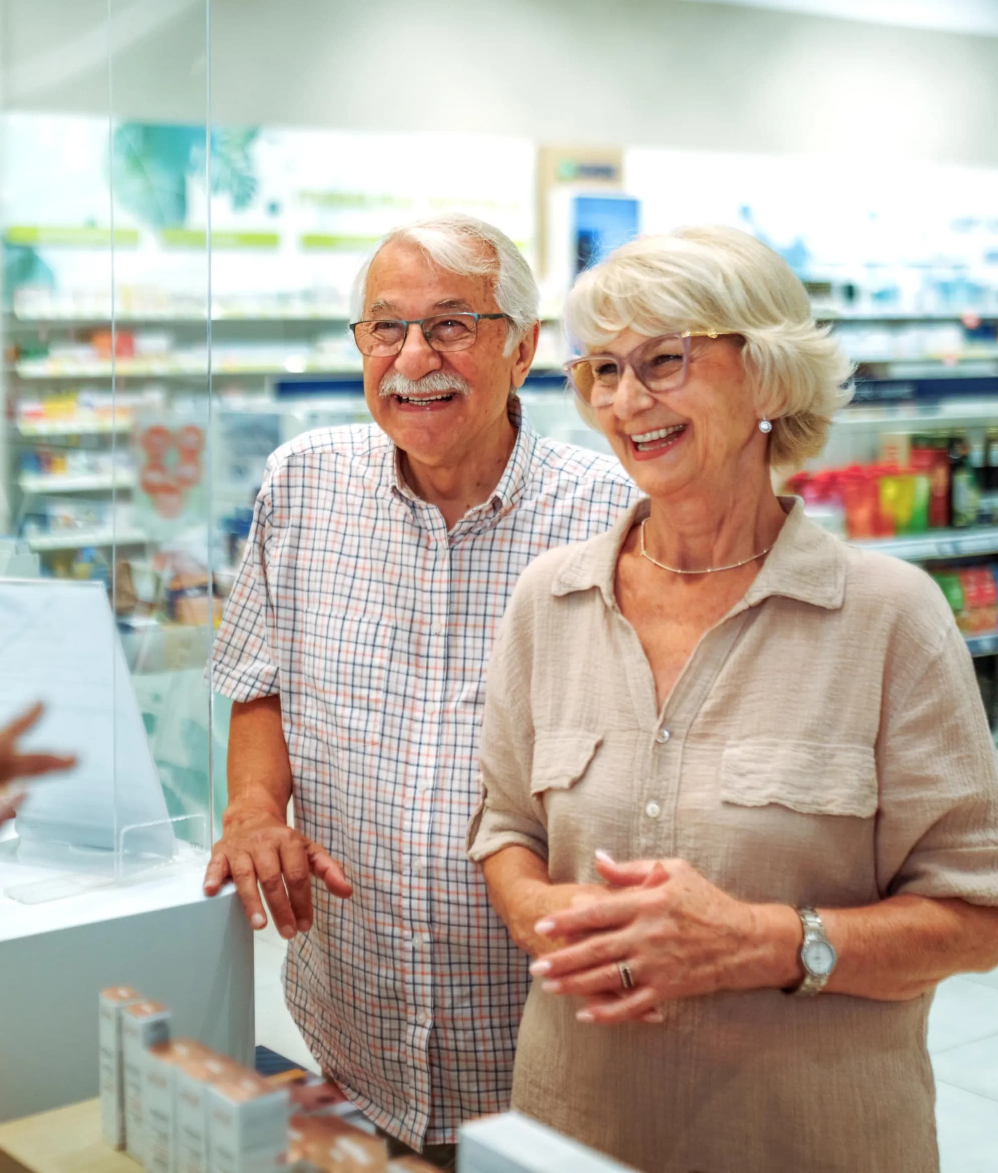 Pharmacy technician assisting a patient at the prescription pickup counter